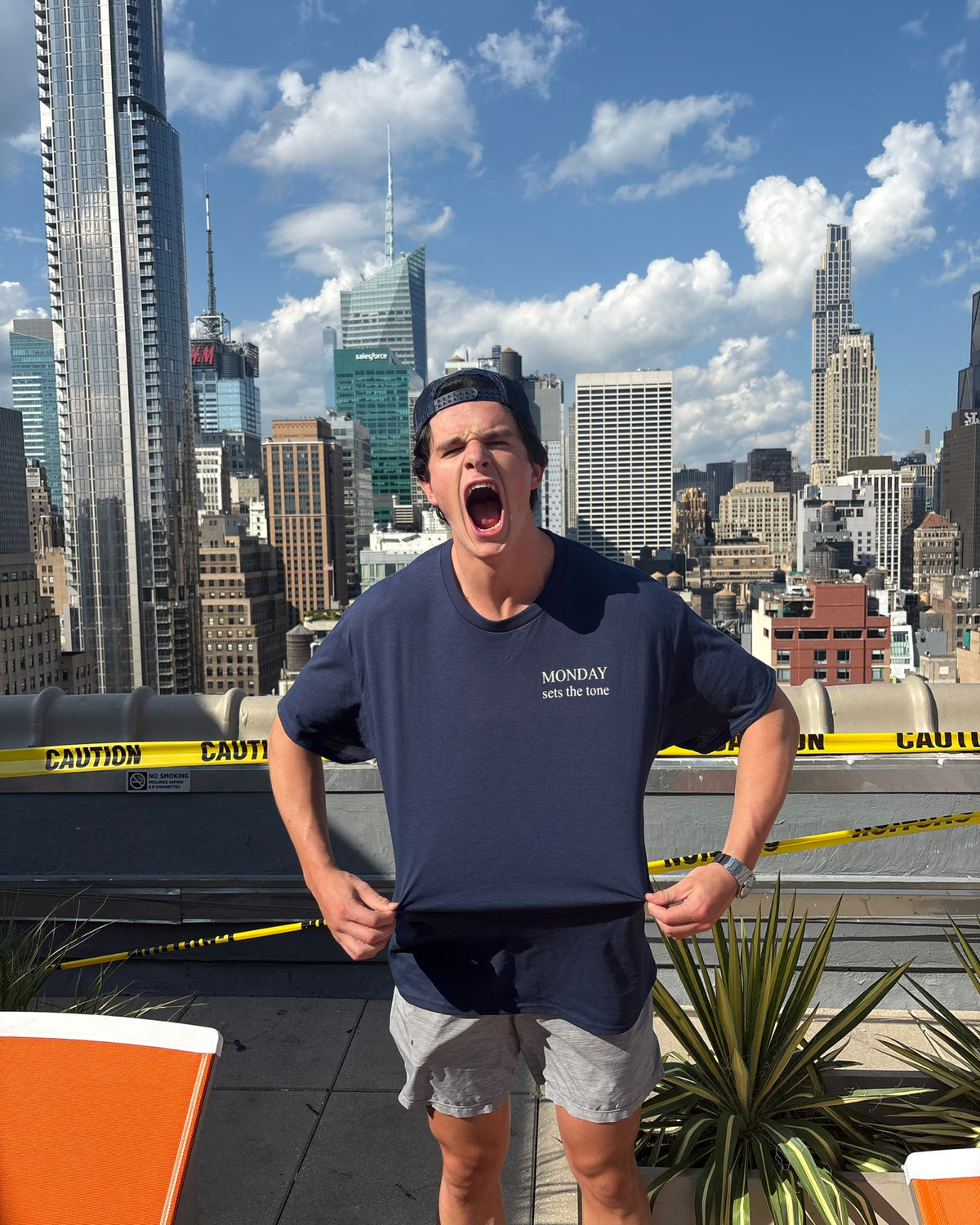 The Monday Tee in navy — front chest mark worn against the New York skyline